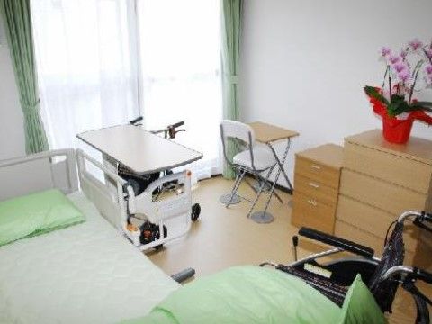 居室には柵付きのベッドが用意されている。タンスもあり、ベッドとの間には入居者様の車椅子が置かれている。