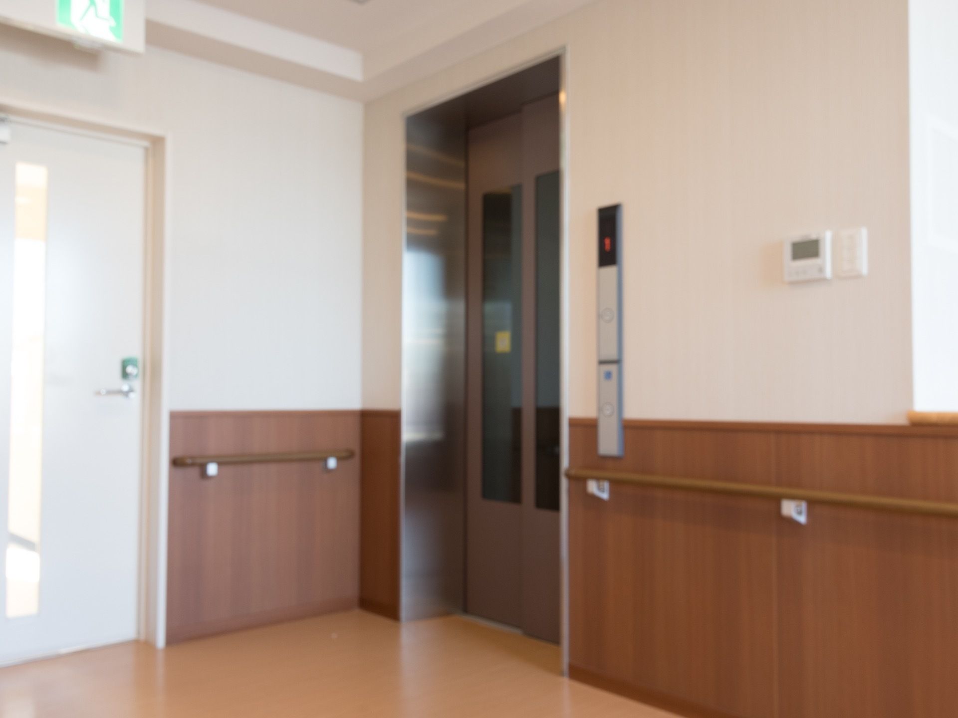 エレベーター前の廊下には、手すりが取りつけられている。すぐ左側に、白い扉の非常階段が設けられている。