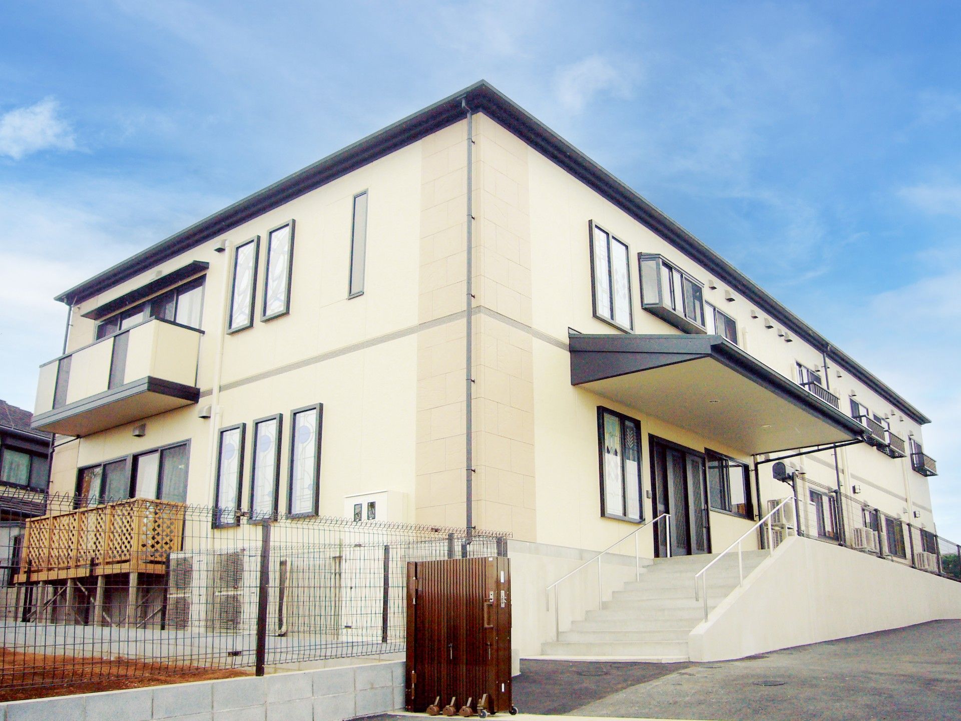 2階建ての建物で、玄関前には屋根を設置している。手すりのついた階段とスロープを設けており、隣には家庭菜園スペースがある。