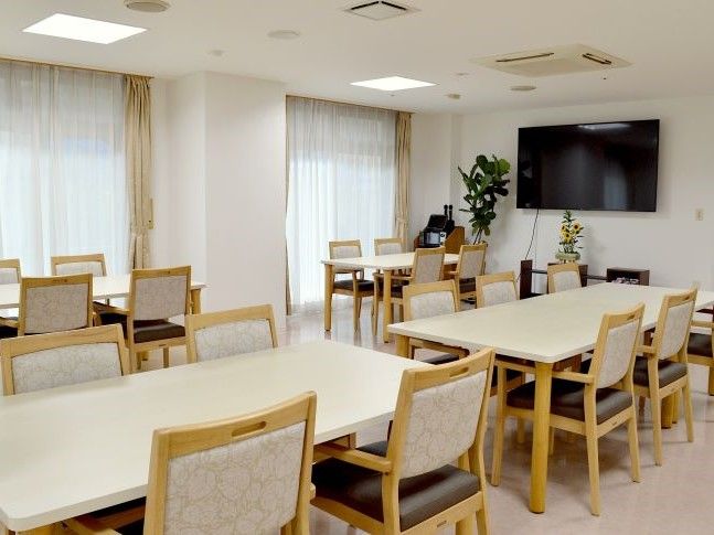 食堂は、開放的な空間になっている。車椅子のまま席に着けるダイニングテーブルが用意されている。テレビが壁に設置されている。