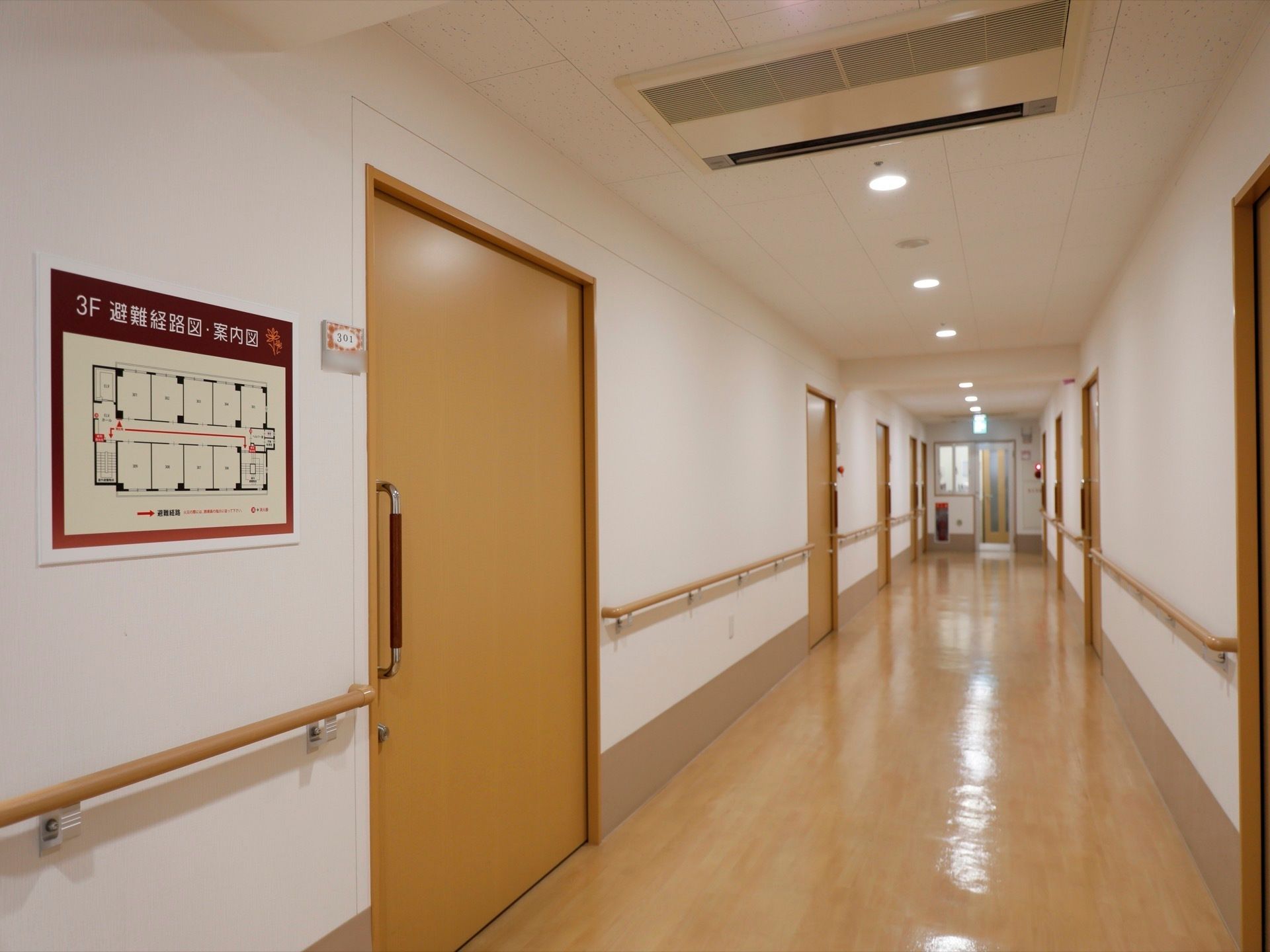 手すりがついた広い通路がある。一直線に続く廊下の壁には、災害時の避難経路を示す案内板が大きく掲示されている。