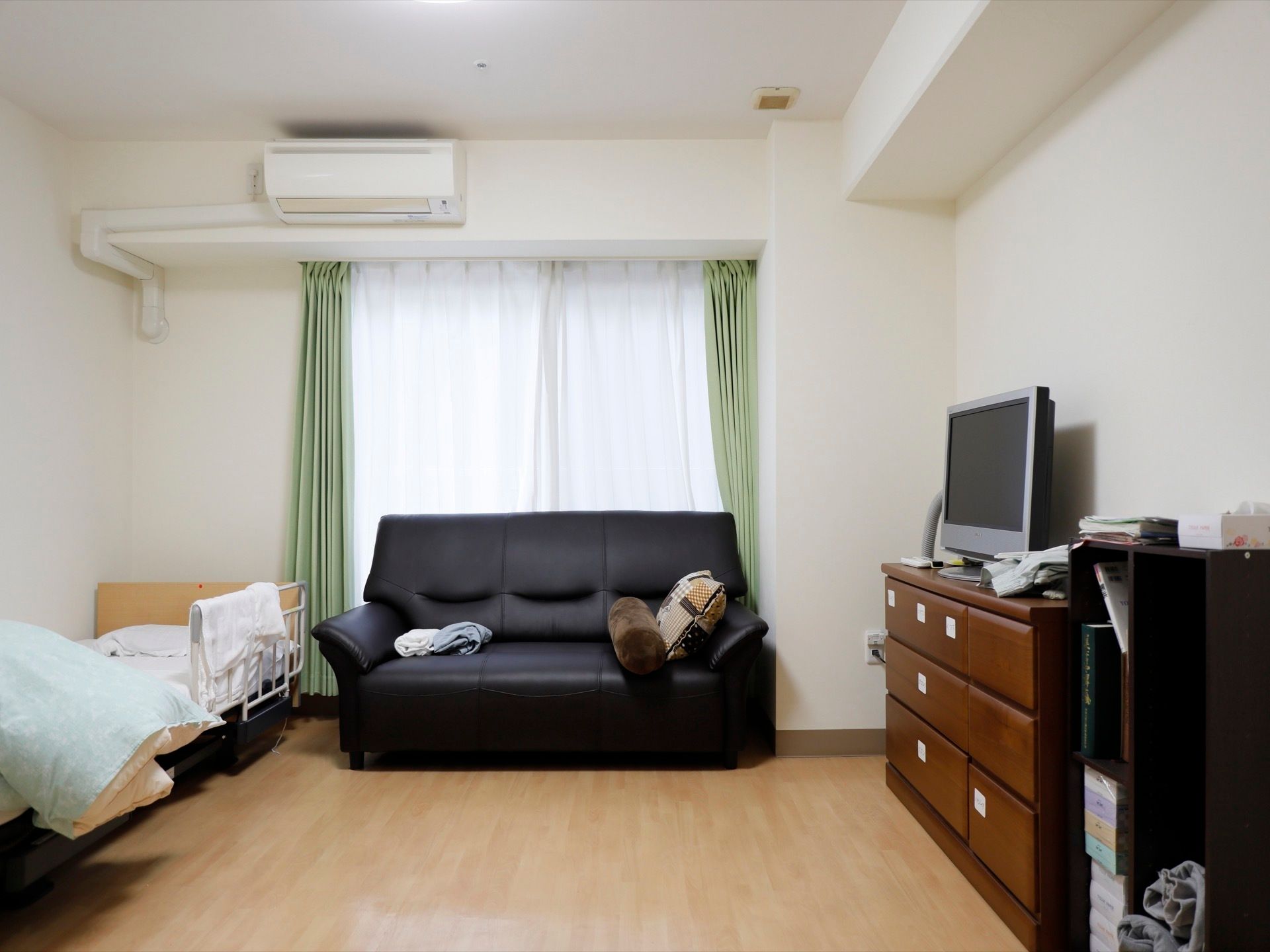 居室の中央に革張りの大きなソファが備え付けられているほか、収納容量の高い箪笥、薄型のテレビもあり、生活のための家具が充実している。