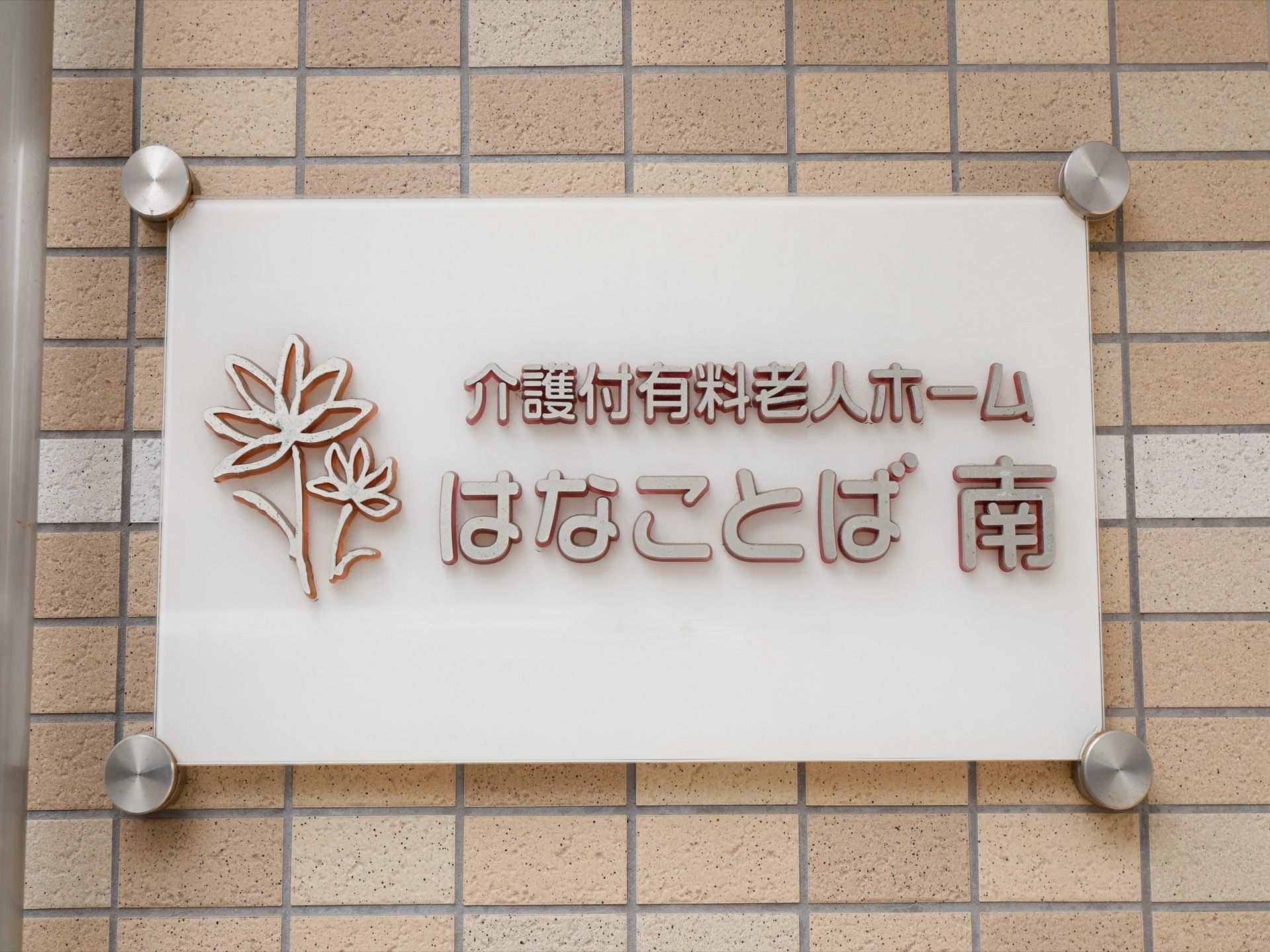 ベージュ色を基調としたレンガ調の外壁に、白色のプレートが掲げられている。プレートには施設名が記されている。