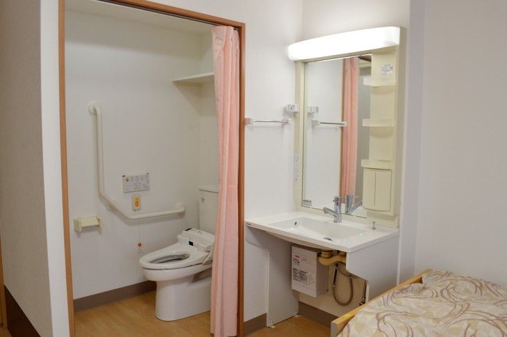 白を基調としたトイレは、排水・洗浄といった機能を備えた各ボタンが壁に取り付けられている。また、スロープも取り付けられている。