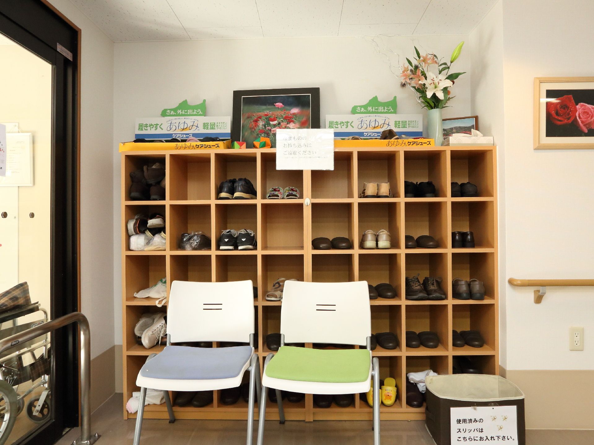 玄関出入口から入って左側には靴箱が設置され、その前には1人掛けの椅子が2つ置かれている。壁には手すりが設置されている。