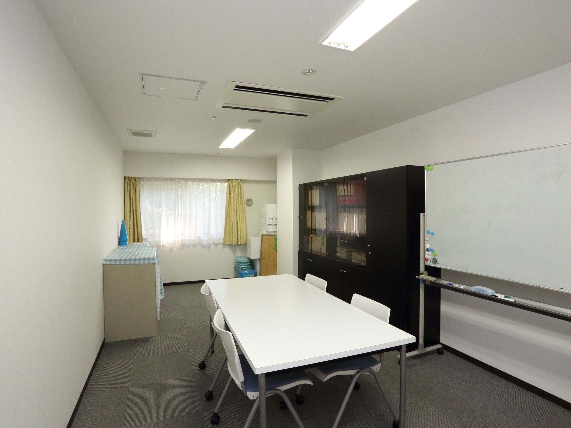 相談室には4人掛けテーブル、ホワイトボード、本棚が置かれている。広く明るい個室で、何でも相談することができる。