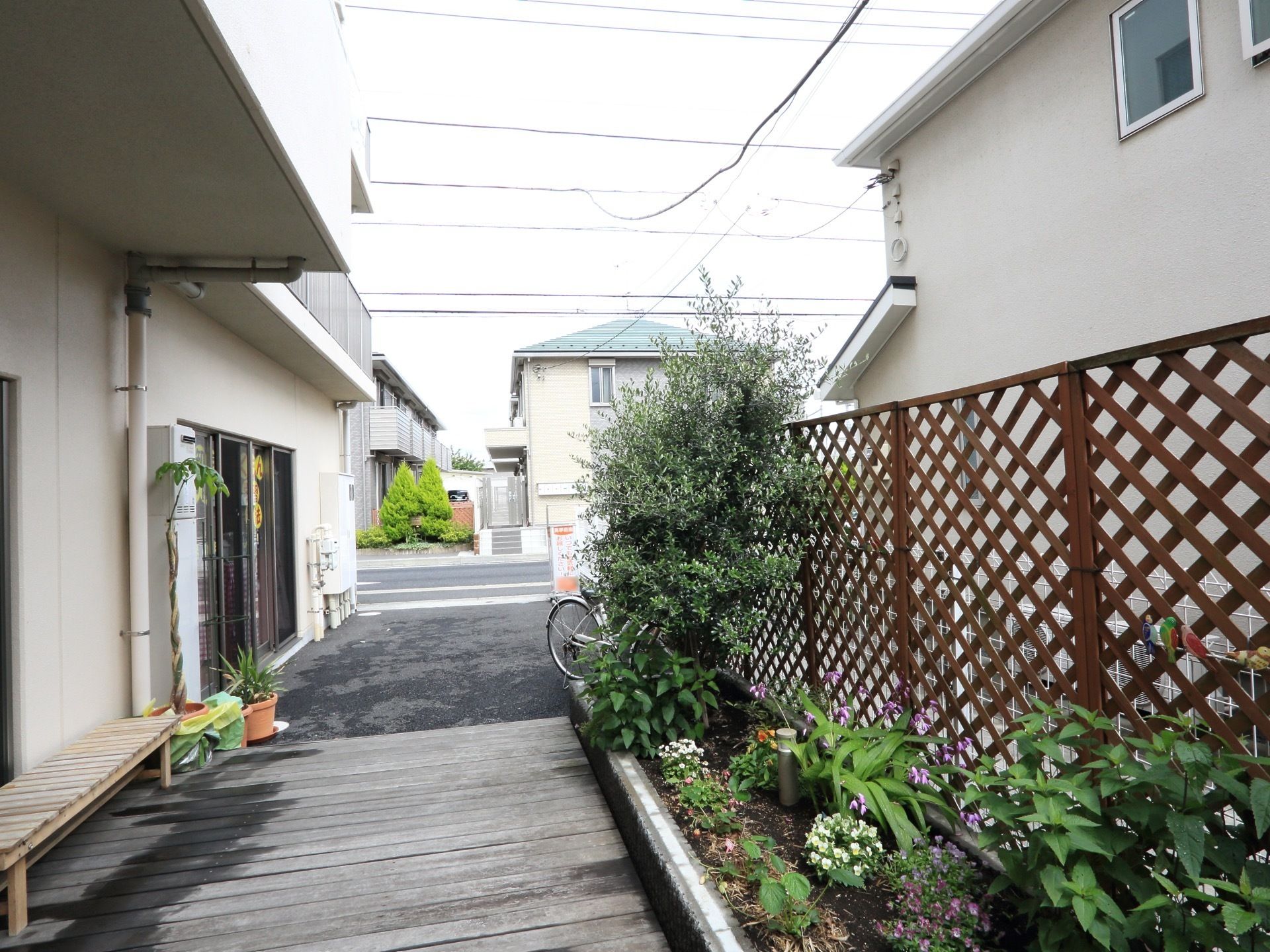 建物の脇には縁台が配置されている。花壇には青々とした樹木や、季節ごとに色どりが変化する花々が植えられている。