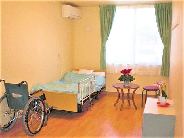 突き当りに腰高窓があり、そのすぐ下に低床型のベッドが置いてある。ベッドの上にはエアコンが設置されている。