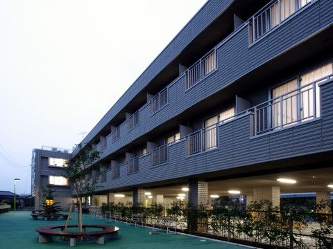 広々とした屋外スペースを背に建っているタイル張りの外壁の建物