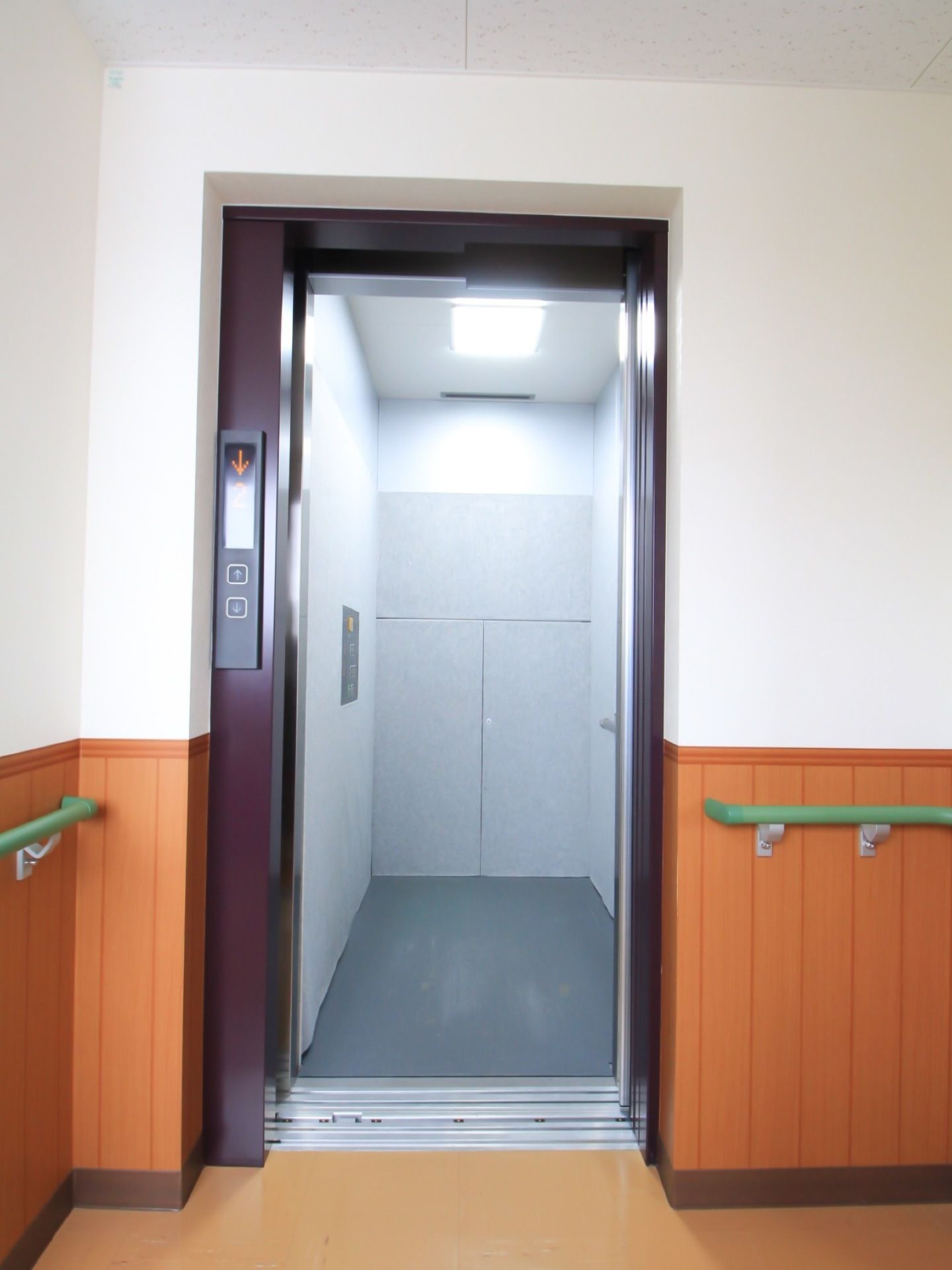 広々としたエレベーターが備え付けられている。通路の壁に腰板が設置され、グリーンの手すりも完備されている。