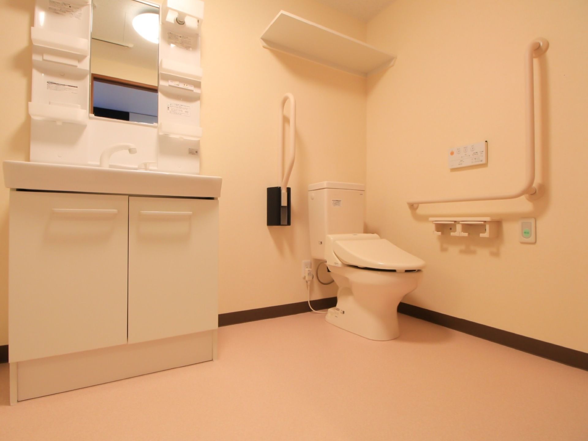 左側には鏡付の洗面台があり、右側には温水洗浄便座付のトイレが設置されている。トイレ側の壁には、手すりが取り付けられている。
