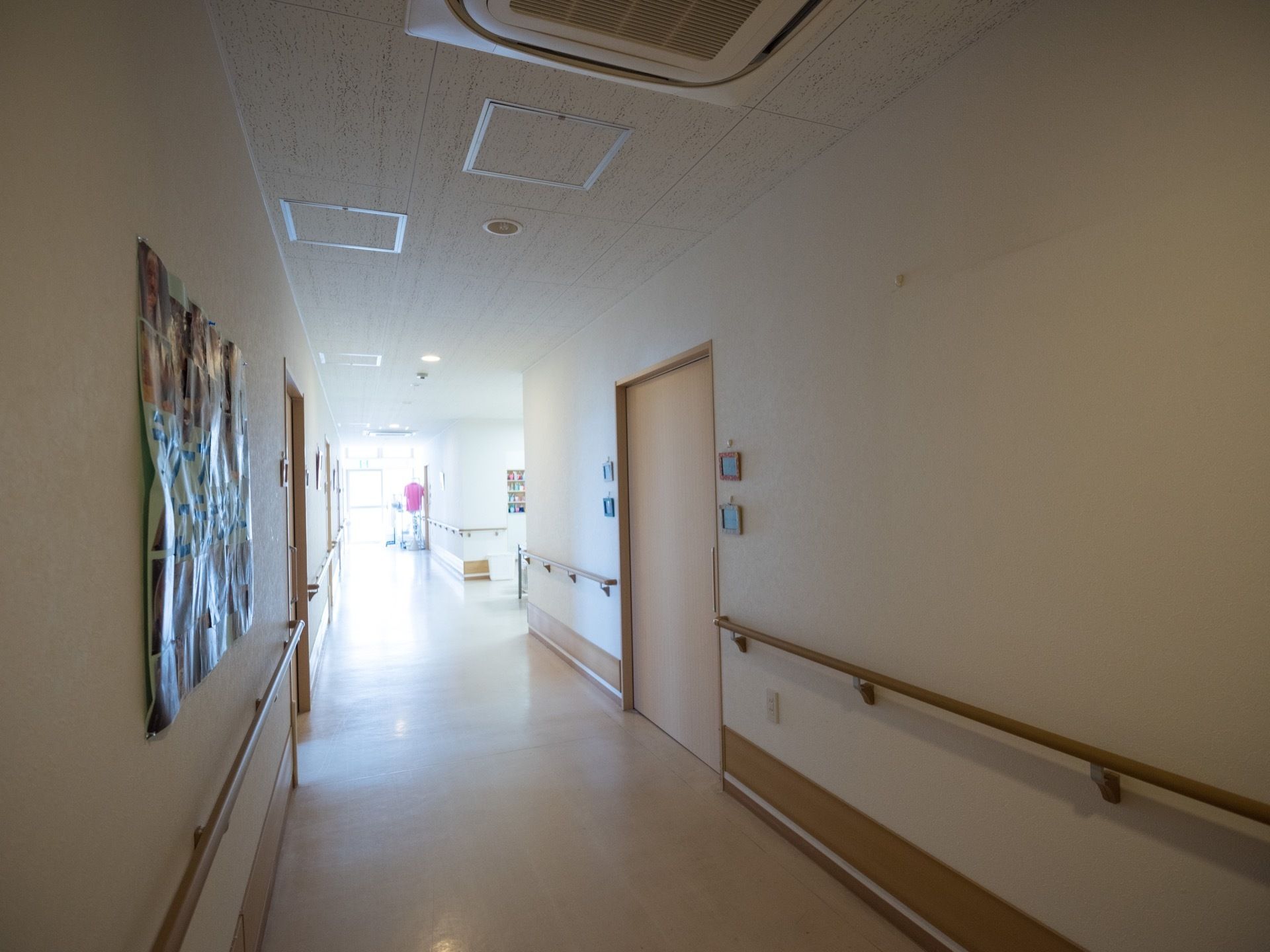 真っ直ぐ伸びた廊下の突き当たりには窓があり、たくさんの外光が差し込んでいる。両側の壁に引き戸があり、壁に名札が下げられている。