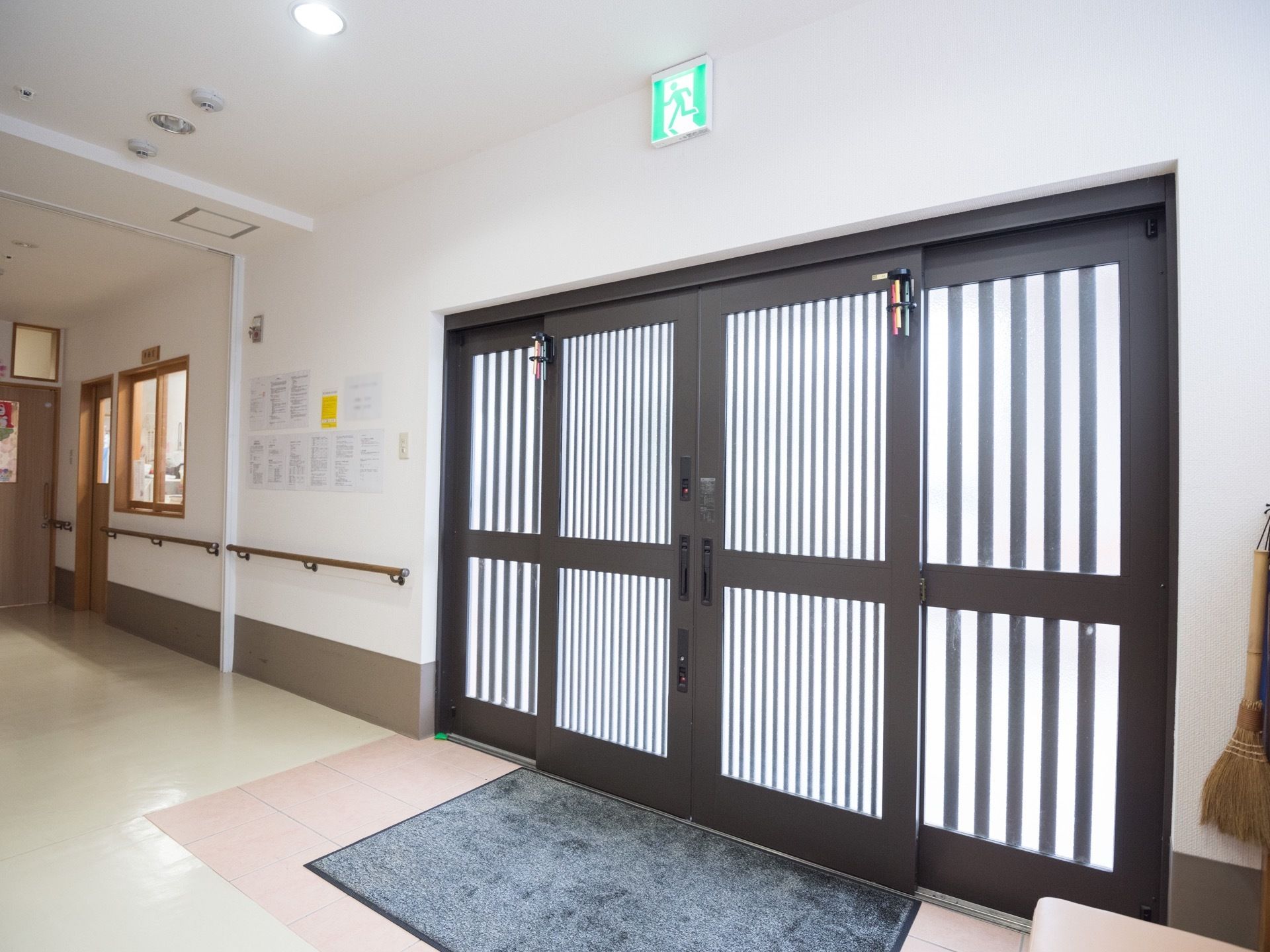 黒い格子にすりガラスの引き戸が付けられた玄関がある。大きな足ふきマットが置かれており、スッキリとした造りになっている。