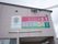 建物の外壁の2階部分に、施設とデイサービスの看板が掲げられている。地元のサッカーチームのロゴマークも描かれている。