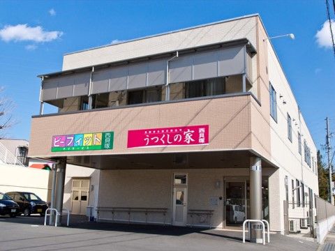 玄関周りだけがベージュに切り替えられた白い外壁で、玄関部に2階が張り出している外観の建物
