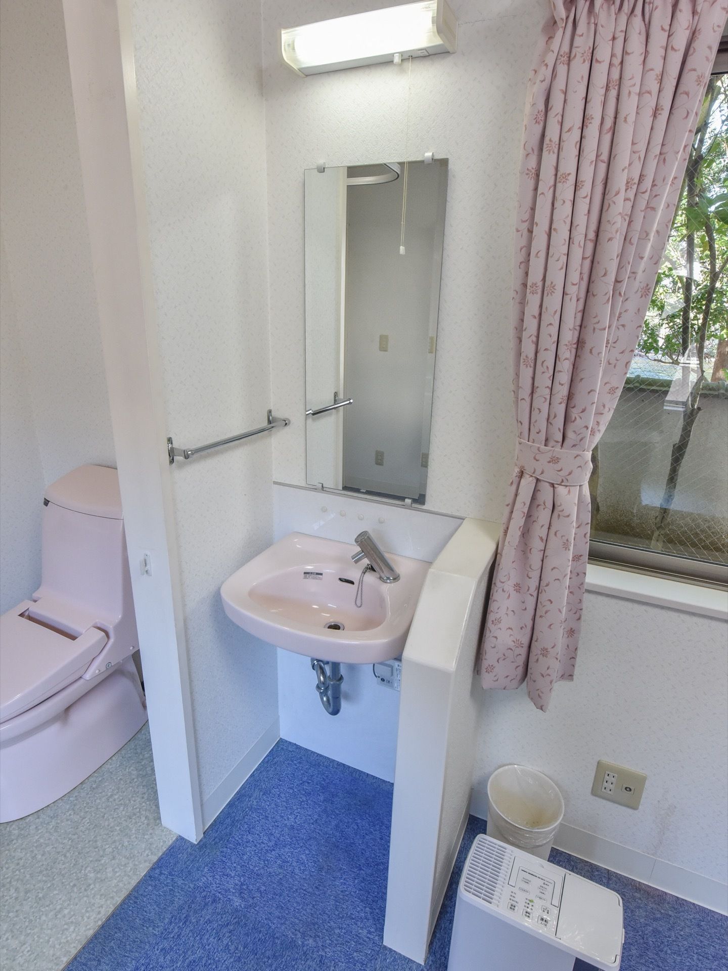 居室のトイレの横に洗面台があり、横には掴まることができるように壁が設置されているため、移動しやすくなっている。