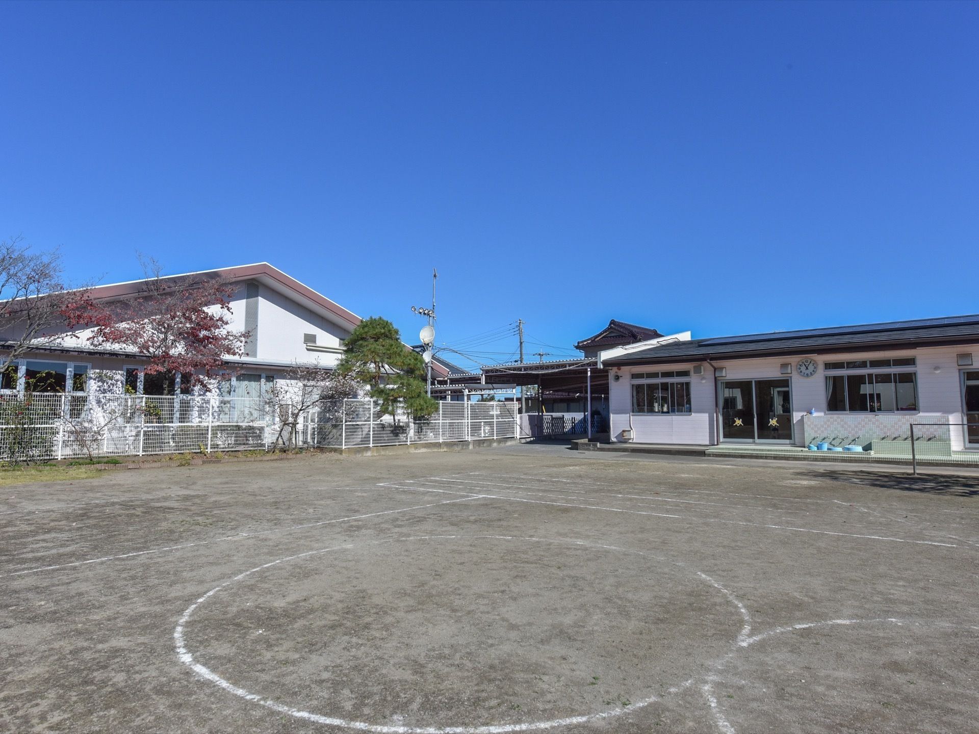 敷地内にはさまざまな種類の木が植えられている。介護施設の隣には併設の保育園の建物があり、広い園庭がある。