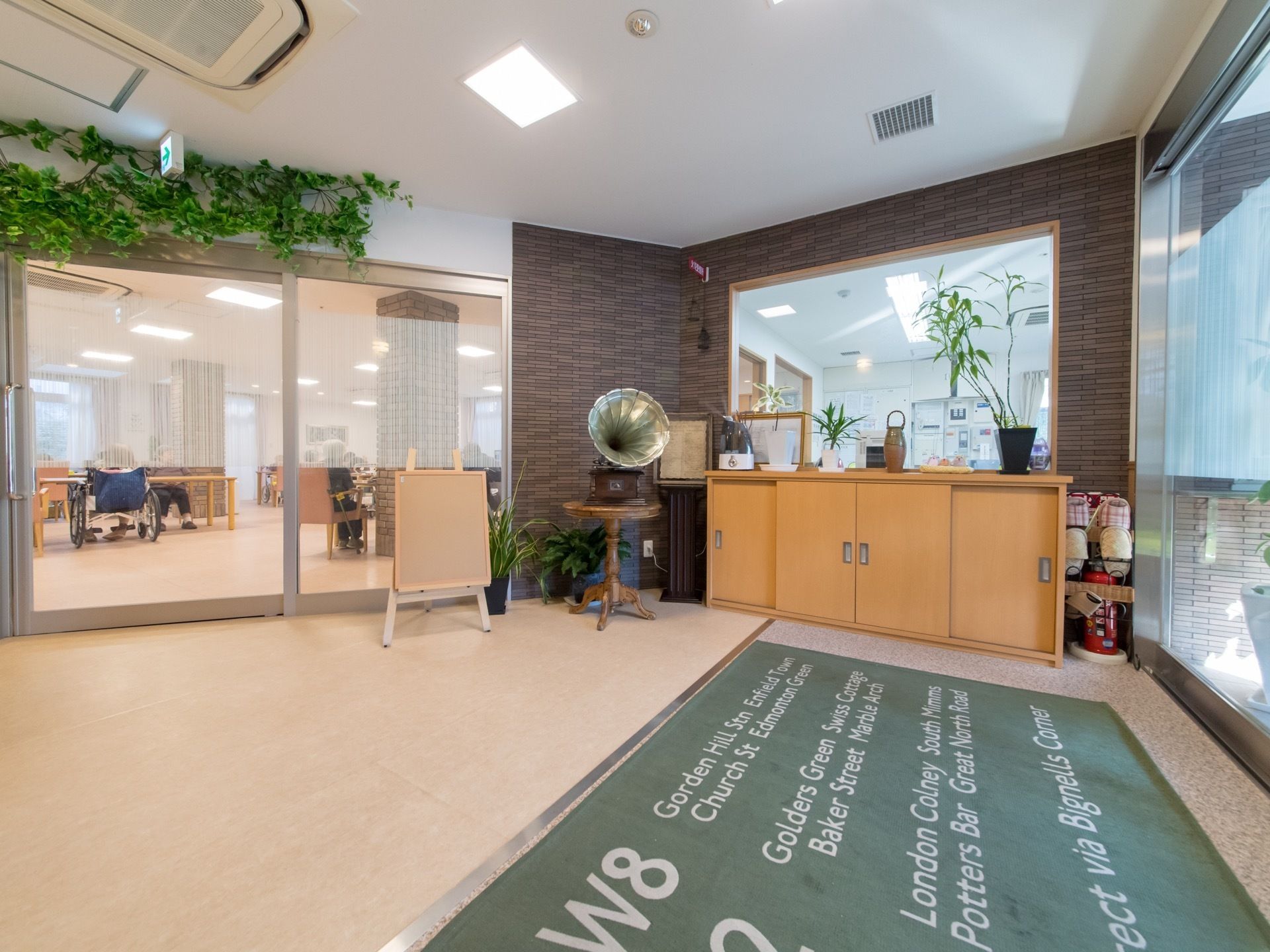 段差がないので車椅子や足腰に不安のある方もスムーズに移動できる。玄関が自動扉になっている。出入り口からスタッフルームが見える。