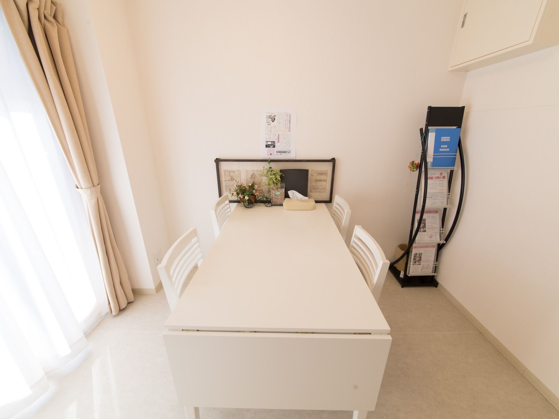 白を基調とした清潔感と高級感のある部屋である。延長が可能なテーブルが置かれている。窓が大きく明るい。資料が置かれている。
