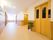 白色と茶色の壁の通路である。手前には黄色い扉のエレベーターがある。広く明るい、開放感のある造りになっている。