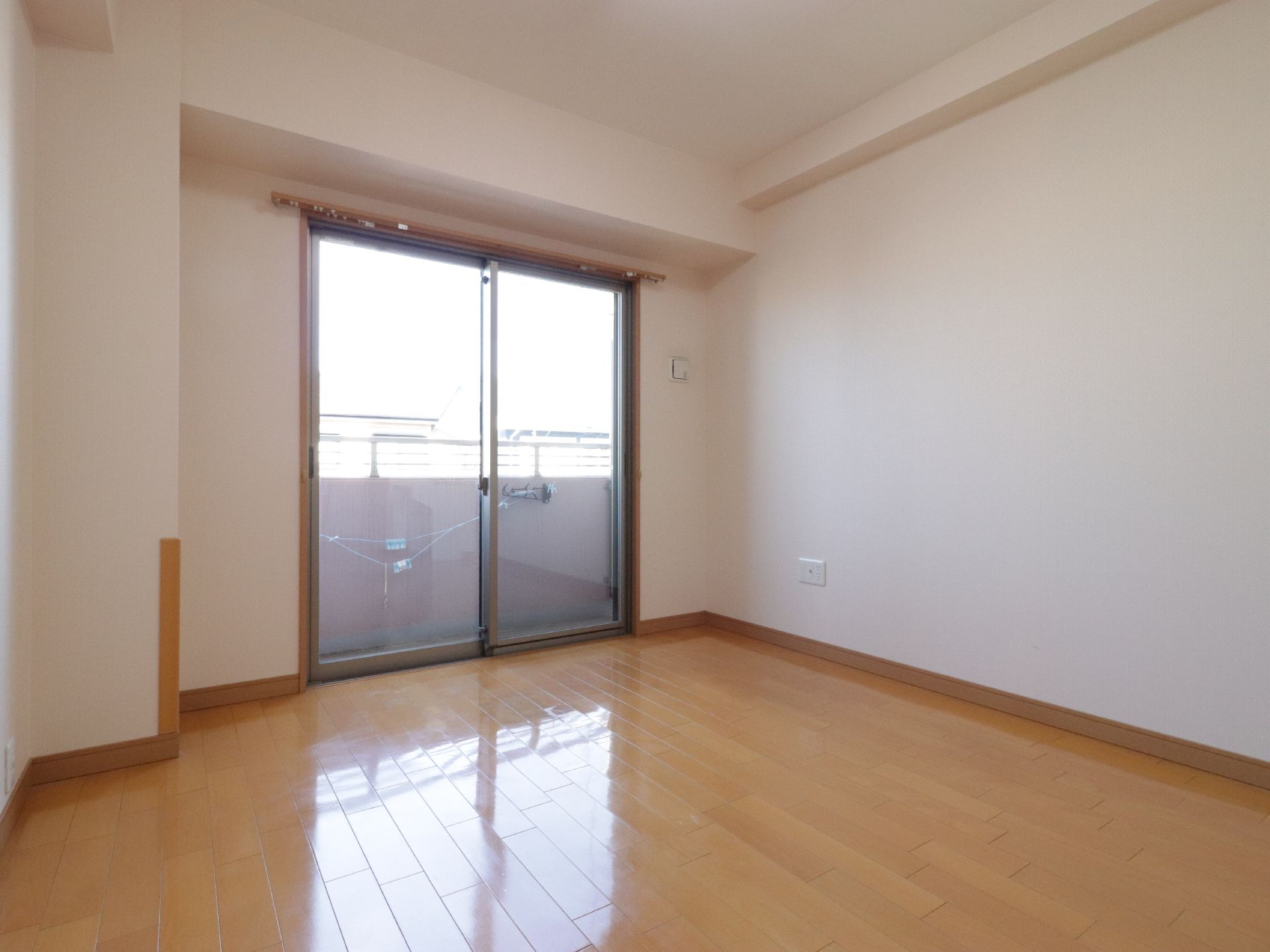 居室の床は光沢のあるフローリング材が使用されている。大きな窓はベランダになっていて開けると外に出られる。