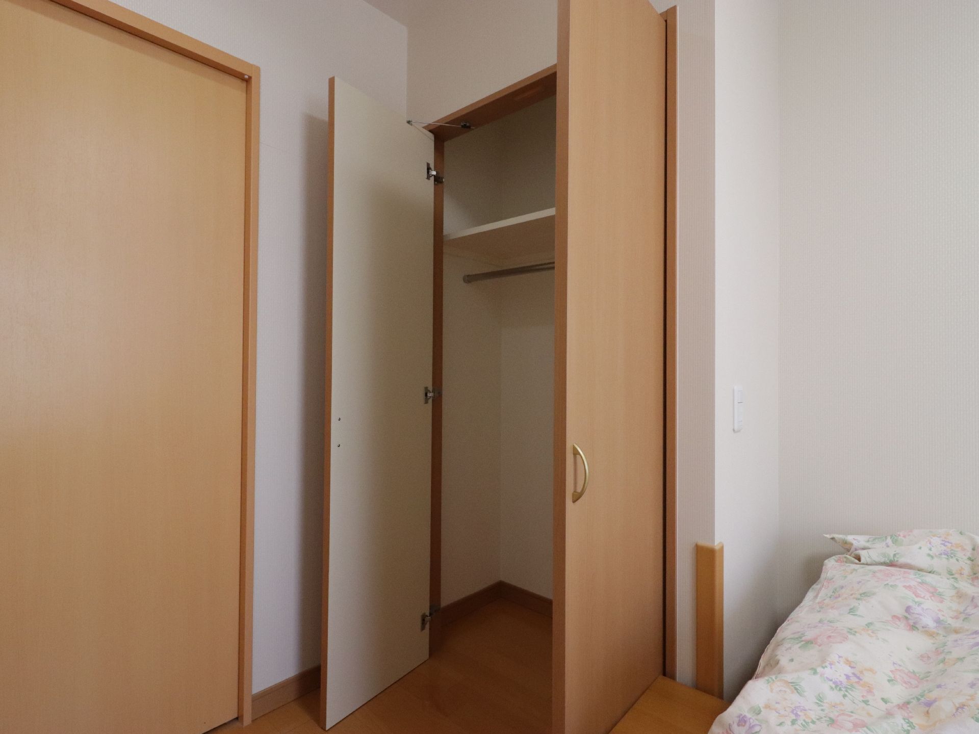 居室のベッドの足元側にレイアウトされた収納クローゼットである。ドアは両開きで、中には服を掛けるパイプが取り付けられている。
