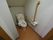 白い壁に茶色の床の清潔感のあるトイレになっている。壁には手すりが設置されており安全に利用することができる。