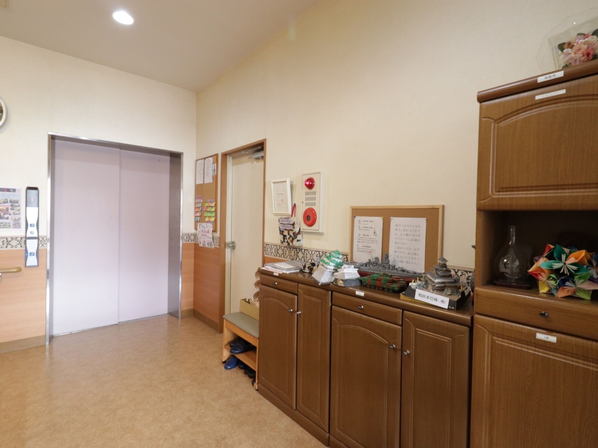玄関先に入居者様が作った作品を名前と共に展示してある。下駄箱など自宅のような雰囲気のデザインでアットホームである。
