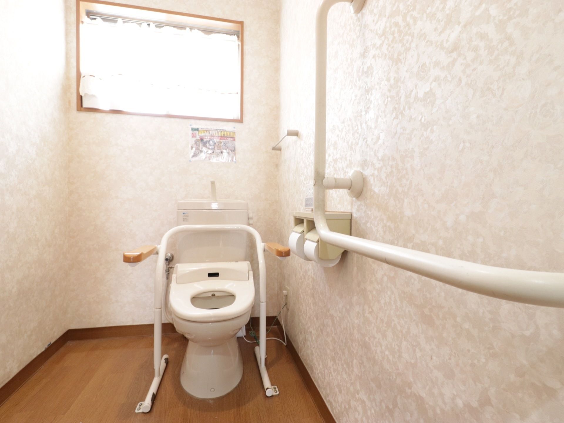 トイレの壁に手すりがあり、便座部分にも設置してある。立ち座りが非常にスムーズに行える。窓から日が差し明るい個室内。