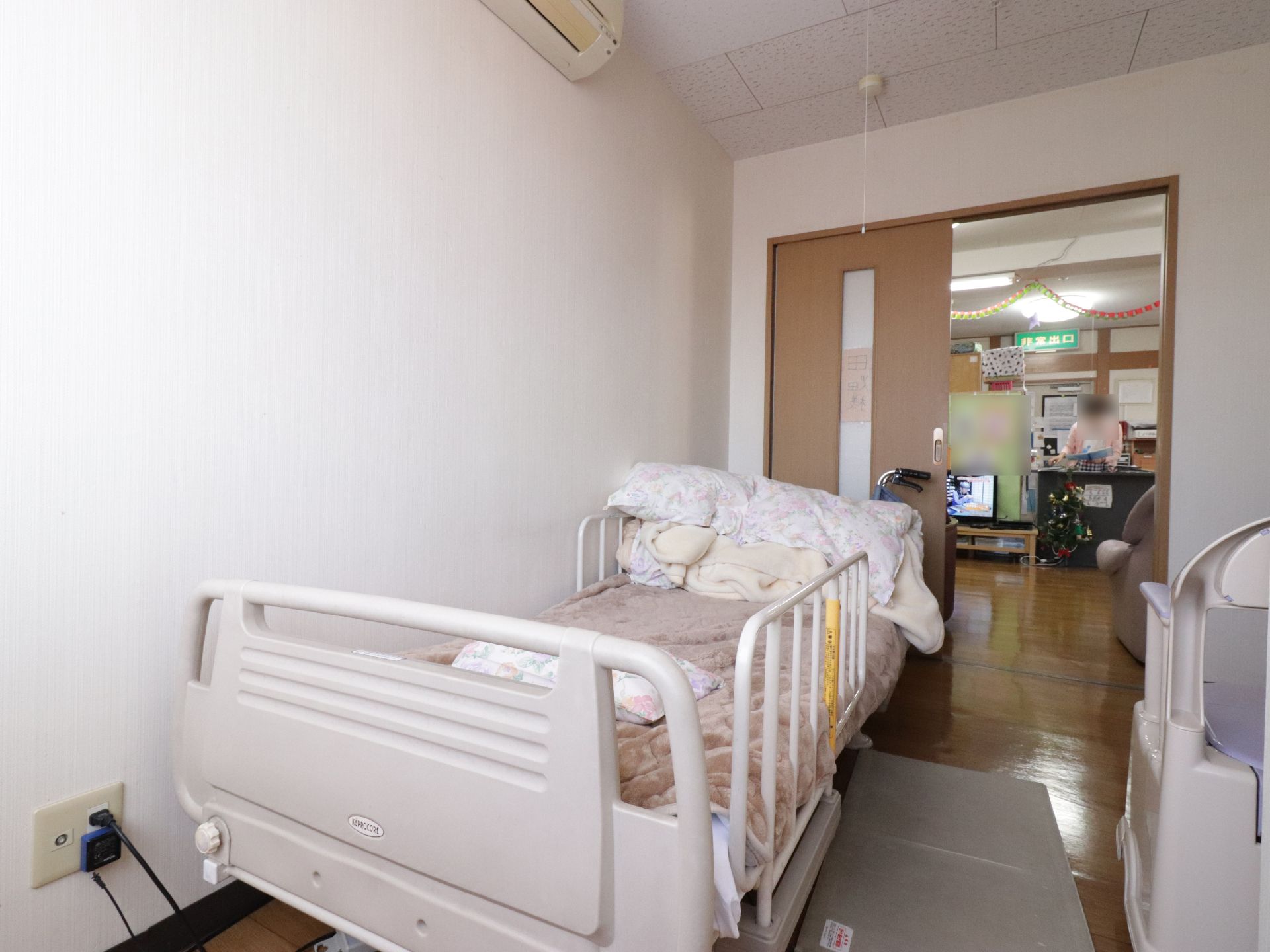居室には布団が敷かれたベッドが置かれている。ベッドの両側には柵が取り付けられている。床には滑り止めマットが敷かれている。