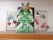 掲示板からはみ出るように画用紙で立体的に作られた大きなクリスマスツリーがある。周りには雪だるまやプレゼントも飾られている。