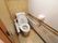 トイレはコンパクトな造りで、洋式便器が設置されている。壁側には長い手すりと鈴が1つ取り付けられている。