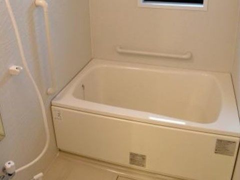 白を基調としたシンプルな個室タイプの浴室である。窓が付いており、壁には白い手すりが取り付けられている。