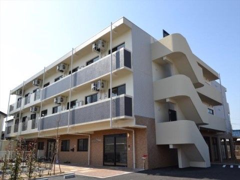 ３階建てのグループホームである。２階以上にはベランダが設けられており、エアコンの室外機が設置されている。