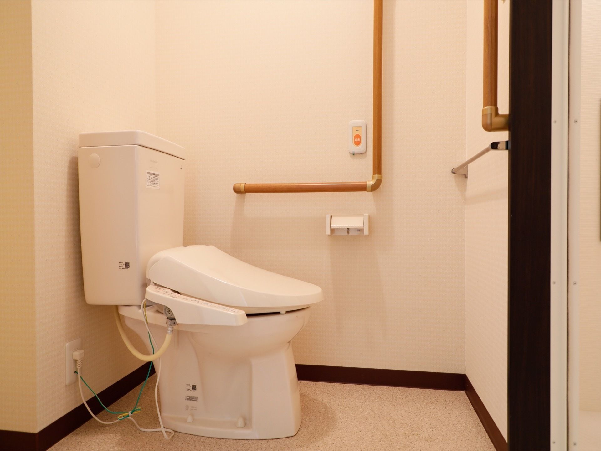 トイレには温水洗浄便座のついた洋式便器を設置している。また壁にはタオル掛けがあり、手すりが取り付けられている。