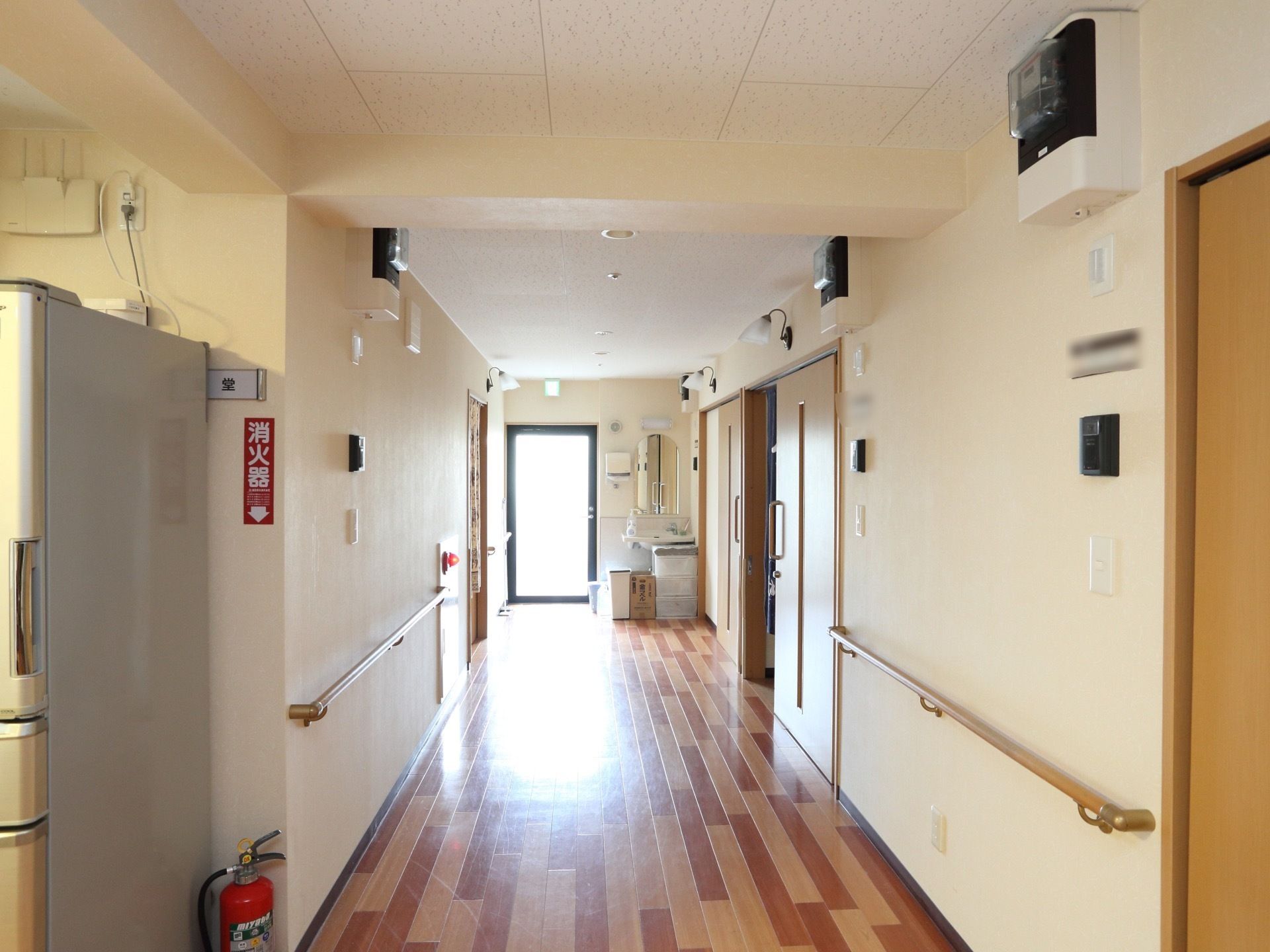 通路の床のフローリングには、ナチュラル系の色とブラウンの２色が使われている。通路の両側に居室が並んでいる。