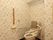 花柄の壁紙が貼られたトイレ。洋式トイレには背あてとひじ掛けが追加されている。壁には手すりとナースコールが付いている。