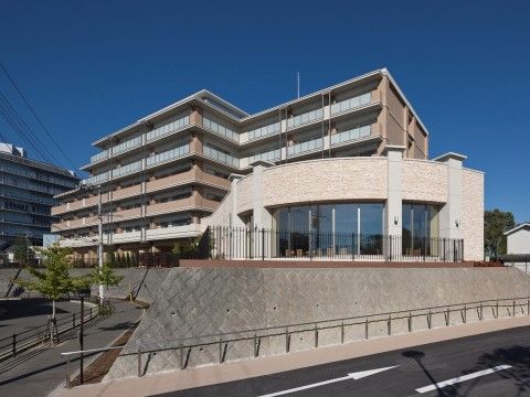 「グッドタイム リビング 千里ひなたが丘」の外観。落ち着いたデザインの建物。円形のガラスデザインが特徴の施設外観となっております。