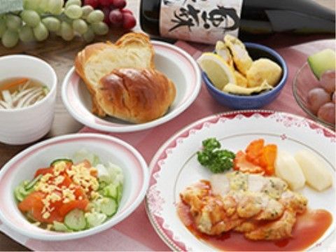 鶏肉のソテーがメインで、ほかに野菜サラダと果物が２皿、パンとコンソメスープが並ぶ。更に日本酒も置いてある。