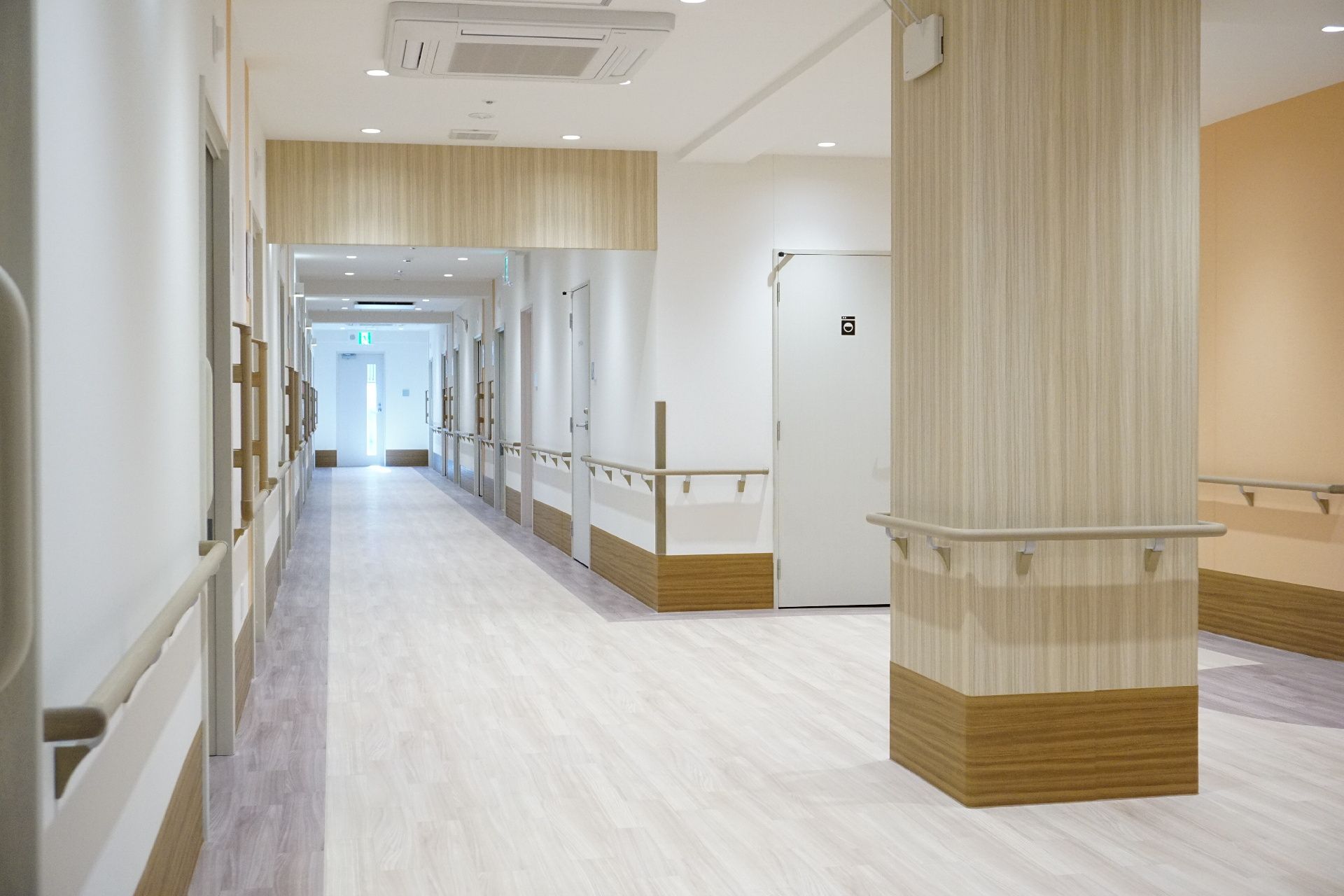 壁に手すりが取り付けられ、休憩用の椅子が置かれている廊下