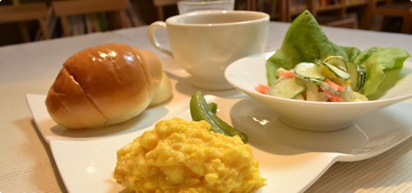 スクランブルエッグやサラダにバターロールがセットになった洋食