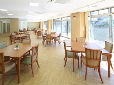 木の質感を感じることのできる室内に、大きな窓からの日の光がたっぷりと差し込んでいる。各テーブルの上には、花がコンパクトに飾られている。