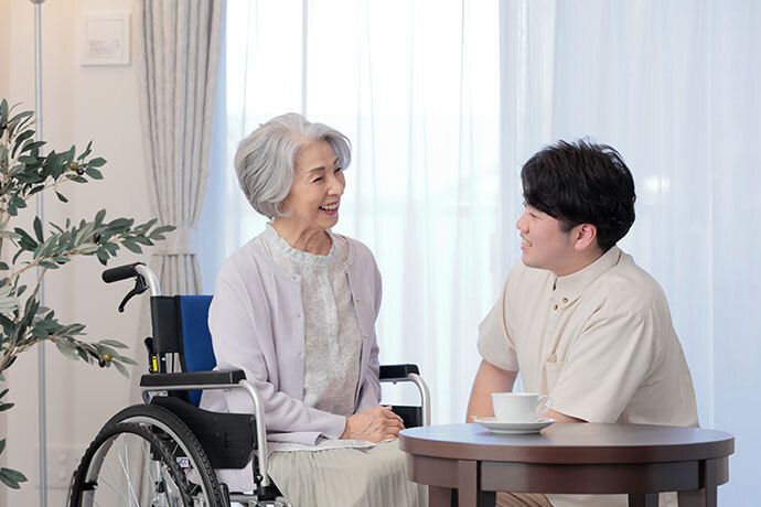 薄いオレンジのシャツにグレーのジャケットを着ている高齢男性と白いブラウスの高齢女性