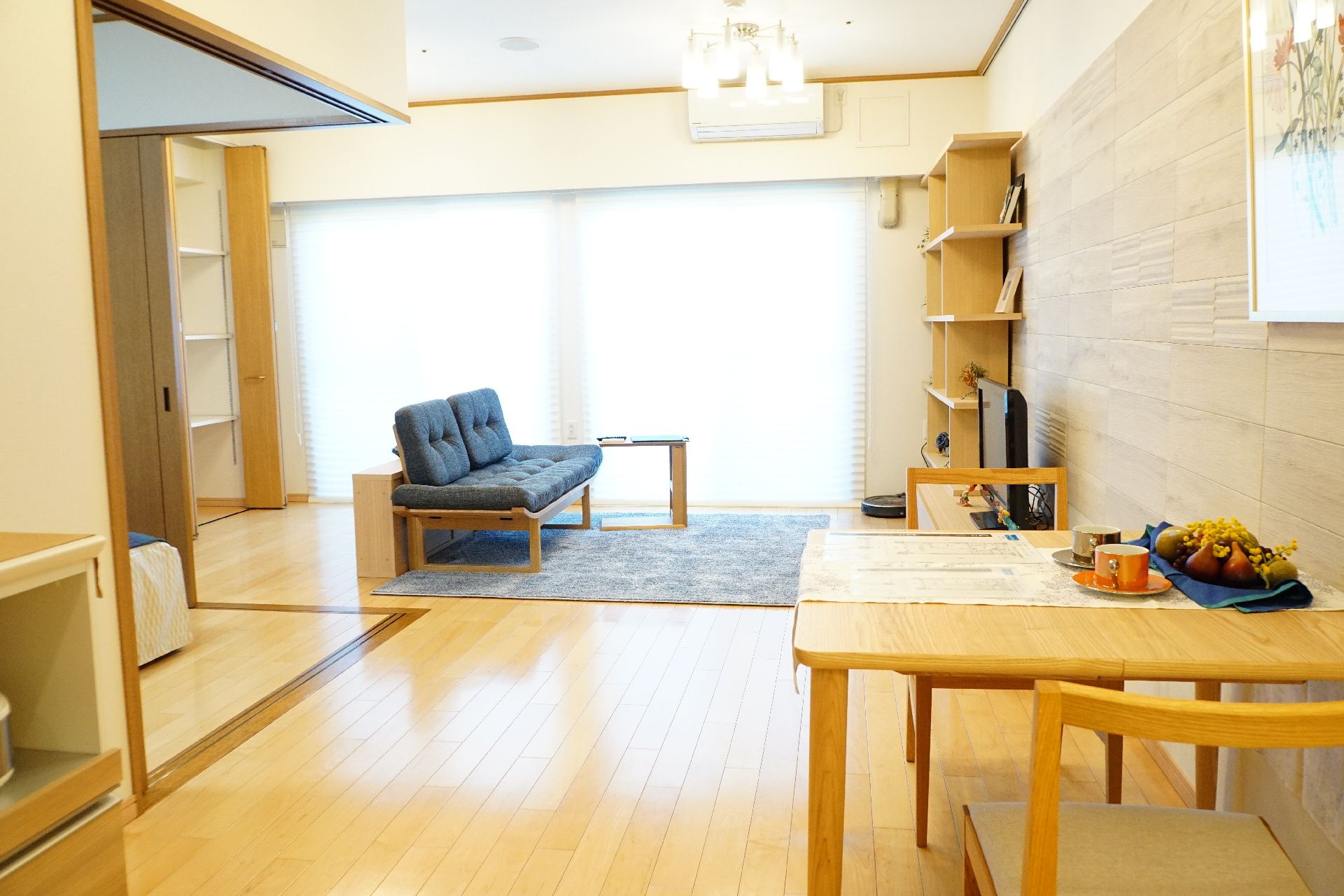 大きな窓があり、棚、テーブル、椅子が置かれている居室
