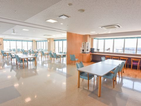 自然光が差し込んで明るく、水色のイスが印象的な食堂