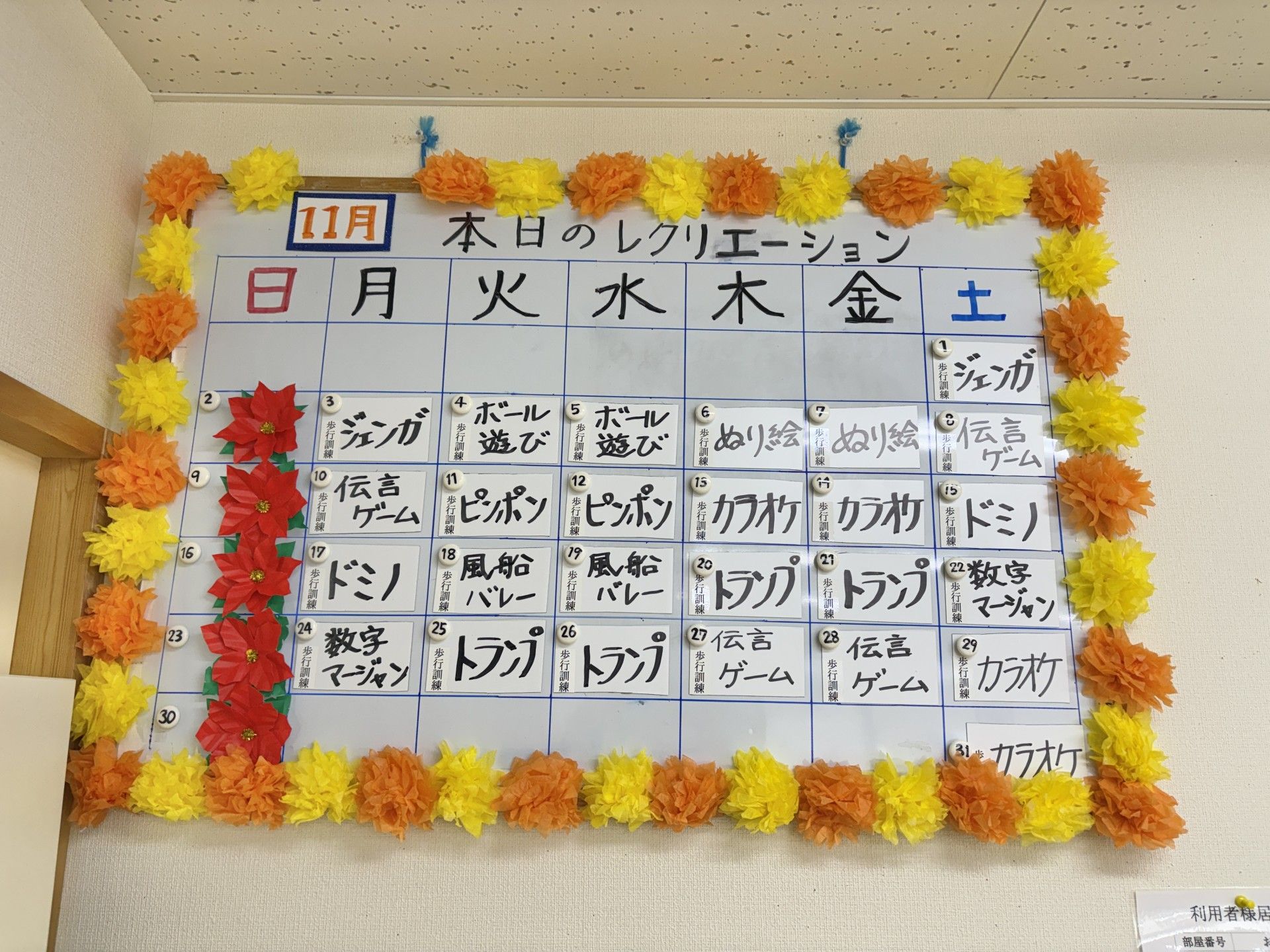 車椅子に座って手を振る高齢女性と後ろで介助をする男性ヘルパー