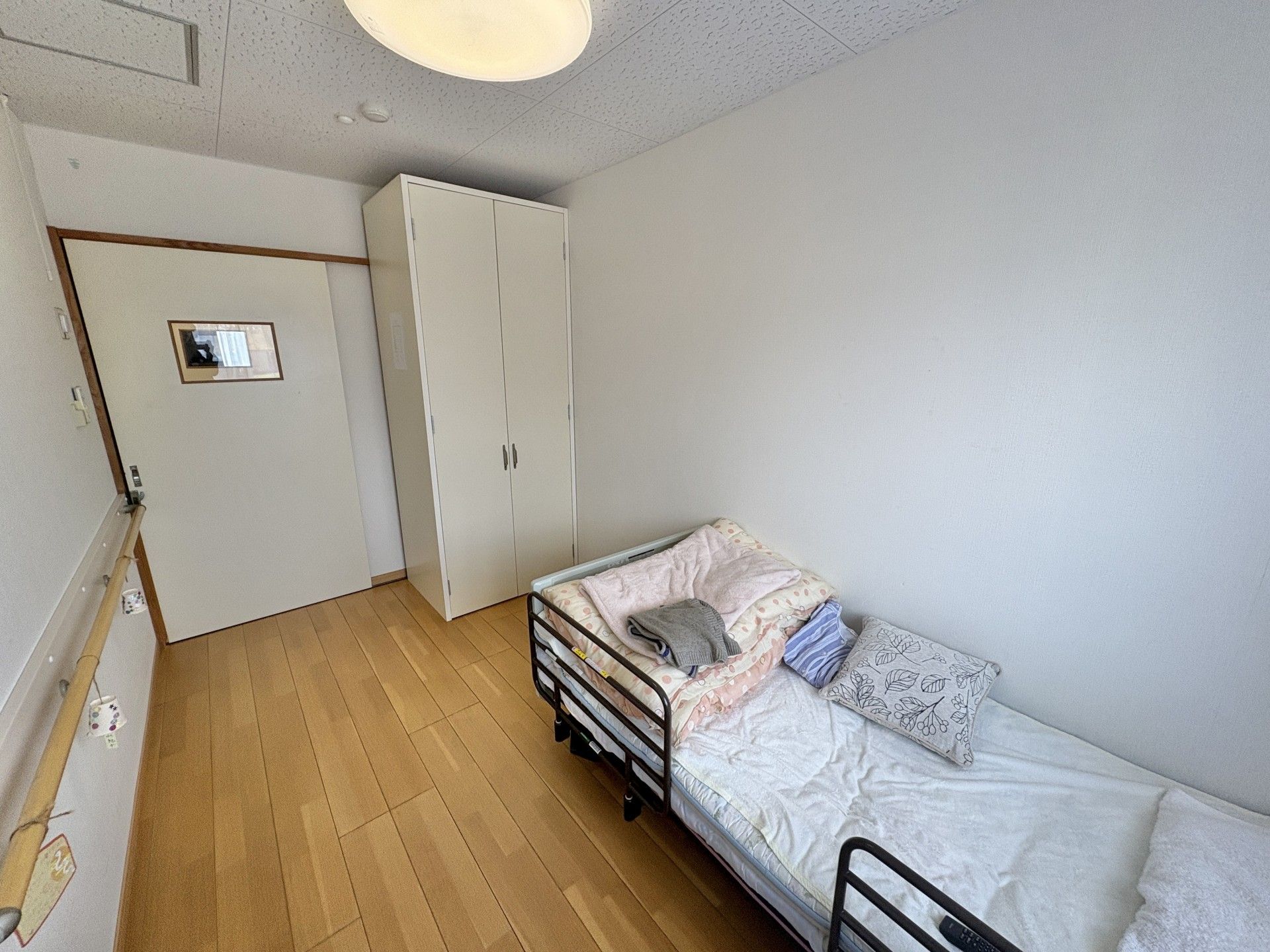 木陰を散歩する車椅子に座っている高齢男性と付き添う女性ヘルパー