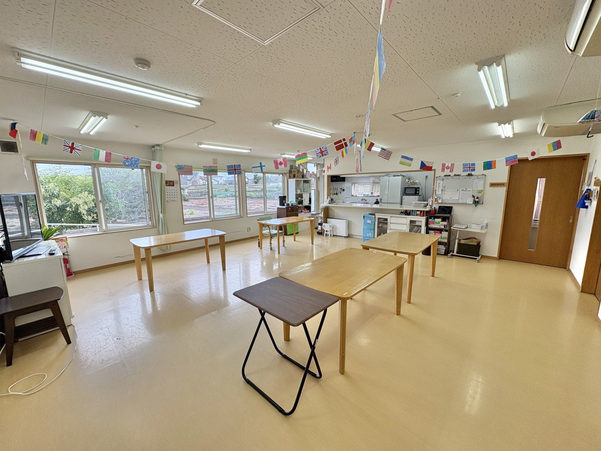 花の咲く道を散歩する車椅子に乗った高齢女性と介助をするヘルパー