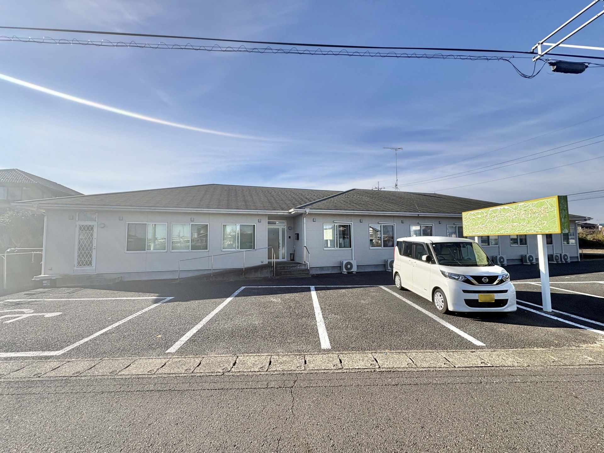 木陰にいる車椅子に乗った高齢男性と付き添う女性ヘルパー