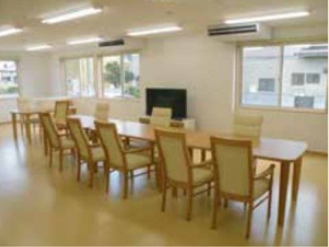 まごころの家 水戸赤塚のリビング。広いリビングにダイニングセットと、テレビが１つ置かれている。